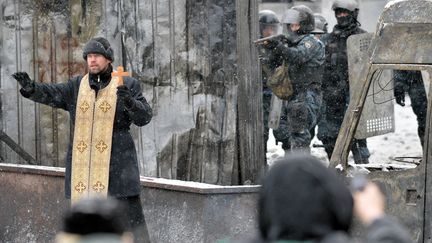 Un pr&ecirc;tre orthodoxe tente de s'interposer entre les manifestants et la police lors d'affrontements &agrave; Kiev (Ukraine), le 22 janvier 2014. (SERGEI SUPINSKY / AFP)