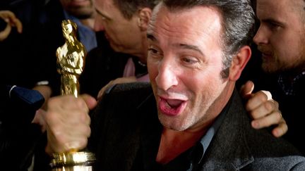 C'est le "winner" de la semaine. Jean Dujardin ne quitte plus sa statuette qu'il brandit fi&egrave;rement &agrave; sa descente d'avion. (MARTIN BUREAU / AFP)