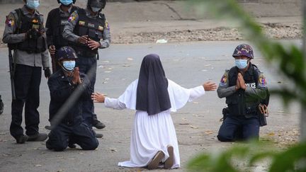 Sœur Ann Roza Nu Thawng à genoux devant les forces de l'ordre, à Myitkyina, dans le nord de&nbsp;la Birmanie. (HANDOUT / MYITKYINA NEWS JOURNAL / AFP)