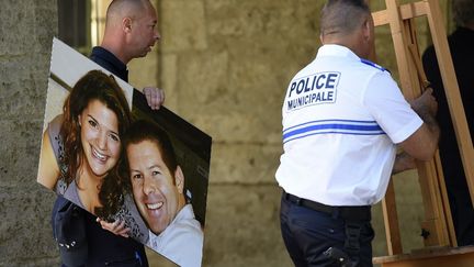 Un policier décrochant une photo de Jean-Baptiste Salvaing et Jessica Schneider, tués dans leur résidence à Magnanville, après un hommage organisé à Pezenas le 20 juin 2016.&nbsp;&nbsp; (SYLVAIN THOMAS / AFP)