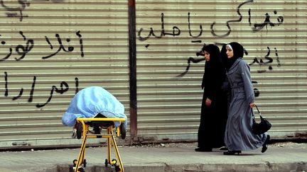 Des Syriennes passent &agrave; c&ocirc;t&eacute; du corps d'un soldat de l'Arm&eacute;e syrienne libre devant l'h&ocirc;pital d'Alep (Syrie), le 28 ao&ucirc;t 2012. (ARIS MESSINIS / AFP)