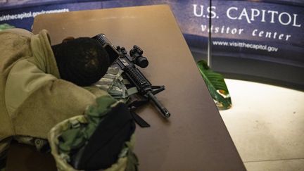 Un militaire de la Garde nationale dort dans le centre pour les visiteurs du Capitole, le 16 janvier 2021. (SAMUEL CORUM / GETTY IMAGES NORTH AMERICA / AFP)