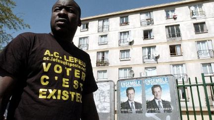 Un membre du collectif AC le Feu devant une affiche de campagne de 2007 à Clichy-sous-Bois (photo d'illustration) (JEAN AYISSI / AFP)