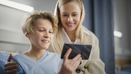 Un enfant utilise un smartphone sous la supervision d'un adulte, le 7 avril 2021. Image d'illustration. (GORODENKOFF PRODUCTIONS/SCIENCE / GPR / AFP)