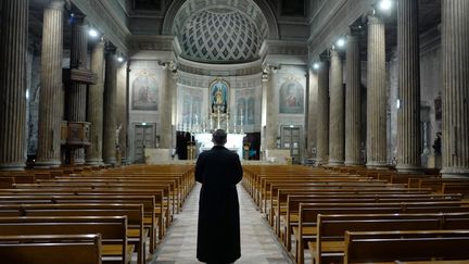 Un prêtre prie, seul dans son église, à Nice, le 27 mars 2020. (VALERY HACHE / AFP)