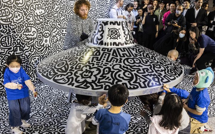 L'artiste Sam Cox, alias Mr Doodle, termine sa performance dans le métro d'Hong Kong entouré d'enfants, dimanche 19 novembre 2023. (ISAAC LAWRENCE / AFP)