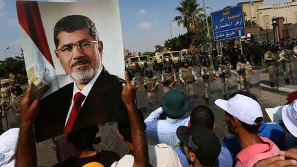 Un partisan des Fr&egrave;res musulmans brandit une pancarte avec la photo du pr&eacute;sident d&eacute;chu Mohamed Morsi lors d'une manifestation au Caire (Egypte), le 19 juillet 2013. (MARWAN NAAMANI / AFP)