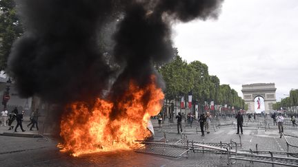 Une poubelle en flammes, dimanche 14 juillet 2019 sur les Champs-Elysées, à Paris. (JULIEN MATTIA / SPUTNIK / AFP)