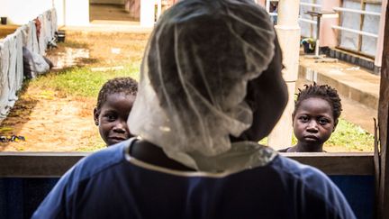 Une infirmi&egrave;re se tient devant deux enfants qui gu&eacute;rissent de la fi&egrave;vre Ebola, &agrave; Freetown (Sierra Leone), le 15 octobre 2014. (MICHAEL DUFF/AP/SIPA)