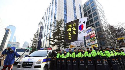 Un manifestant sud-coréen devant le siège du parti Saenuri, à Séoul le 3 décembre 2016, brandit un drapeau national et un slogan «Le peuple est la constitution!» (JUNG Yeon-Je / AFP)