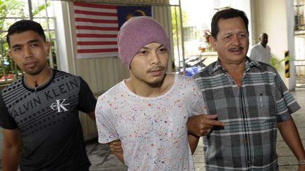 Sur cette photo, le chanteur Namewee escorté par deux policiers en civil dans un tribunal à Panang, au nord-ouest de la Malaisie, le 22 août 2016. (Gary Chuah/AP/SIPA)