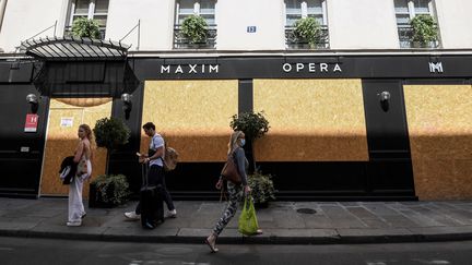 Des passants devant l'hôtel Maxim Opéra fermé, le 6 août 2021. (ALAIN JOCARD / AFP)