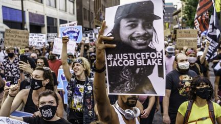 Des manifestants à Minneapolis (Minnesota), brandissent le portrait de Jacob Blake, le 24 août 2020.&nbsp; (KEREM YUCEL / AFP)