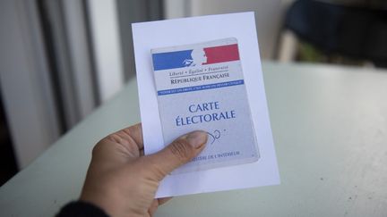 Une femme tient sa carte électorale, le 10 juin 2022 à Paris. (MAGALI COHEN / HANS LUCAS / AFP)