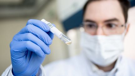 A Munich, un médecin tient un échantillon dans un laboratoire Covid-19. (MATTHIAS BALK / DPA)