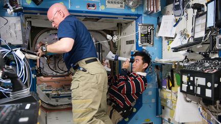 L'astronaute américain Scott Kelly (à gauche) et le Japonais&nbsp;Kimiya Yui, en plein travail, dans la Station spatiale internationale, le 5 août 2015. (NASA / AFP)