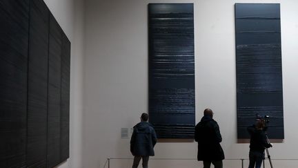 A droite, deux des trois tableaux que Pierre Soulages vient de peindre, accrochés au Louvre, au Salon carré (6 décembre 2019) (FRANCOIS GUILLOT / AFP)