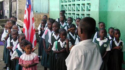 Des élèves libériens dans la cour de leur école saluent le drapeau de leur pays.&nbsp; (? REUTERS PHOTOGRAPHER / REUTER / X01095)