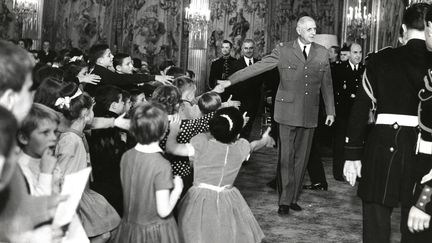 Les enfants se ruent vers Charles de Gaulle &agrave; son entr&eacute;e dans le salon de l'Elys&eacute;e, le 10 d&eacute;cembre 1964.&nbsp;Yvonne de Gaulle choisit elle-m&ecirc;me qui choisit les cadeaux et les spectacle, bien que le G&eacute;n&eacute;ral ait une pr&eacute;f&eacute;rence pour les clowns de cirque, &eacute;crit Fr&eacute;d&eacute;rique Neau-Dufour dans Yvonne de Gaulle (2010, &eacute;d. Fayard). (PHOTOVINTAGES / AFP)