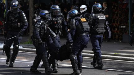 Des policiers aident un policier blessé lors d'une manifestation le 1er mai à l'occasion de la journée internationale des travailleurs et des travailleuses, à Paris, le 1er mai 2023. (GEOFFROY VAN DER HASSELT / AFP)