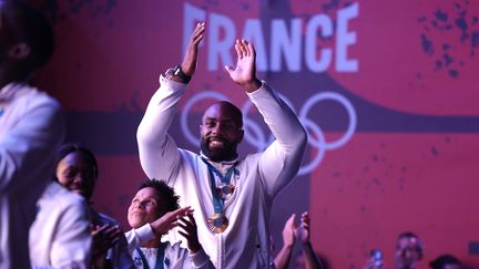 Teddy Riner célébré en héro avec l'équipe de France de judo, samedi 3 août, au Club France. (VALENTINE CHAPUIS / AFP)