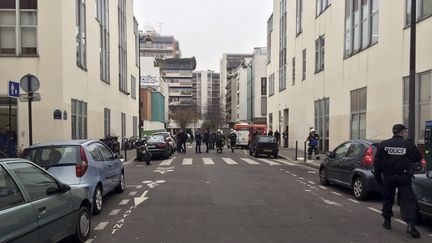 Des policiers et des pompiers devant le si&egrave;ge de "Charlie Hebdo", dans le 11e arrondissement &agrave; Paris, apr&egrave;s l'attentat terroriste survenu le 7 janvier 2015. (PHILIPPE DUPEYRAT / AFP)