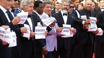 Sylvester Stallone (C) et le casting du film "The Expendables 3" posent avec des pancartes "Bring back our girls" lors de la mont&eacute;e des marches &agrave; Cannes (Alpes-Maritimes), le 18 mai 2014. ( YVES HERMAN / REUTERS)