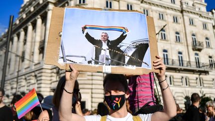 Un manifestant tient une pancarte avec une photo du Premier ministre hongrois Viktor Orbán, lors d'un rassemblement à Budapest (Hongrie) contre la loi interdisant la "promotion" de l'homosexualité le 14 juin 2021. (GERGELY BESENYEI / AFP)