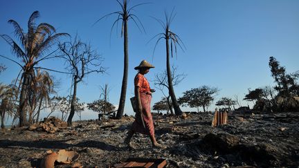 Une femme, de l'ethnie Rakhine, marche sur les d&eacute;bris de maisons incendi&eacute;es, le 27 octobre 2012. (SOE THAN WIN / AFP)