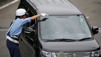 Un policier oriente un conducteur, le 26 juillet 2019, à Sagamihara (Japon). (ISSEI KATO / REUTERS)