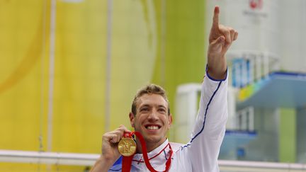 Alain Bernard arbore sa médaille d'or conquise sur 100 mètres nage libre aux Jeux de Pékin, en 2008. (PATRICK B. KRAEMER / EPA / MaxPPP)