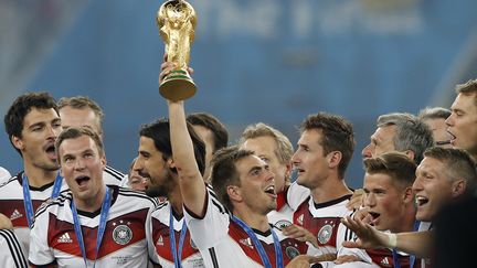 Le capitaine de la Mannschaf, Philipp Lahm, soul&egrave;ve la Coupe du monde, apr&egrave;s sa victoire contre l'Argentine, en finale, &agrave; Rio de Janeiro (Br&eacute;sil), le 13 juillet 2014. (ADRIAN DENNIS / AFP)