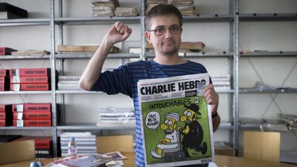 Charb, le directeur de la publication de "Charlie Hebdo", tient un exemplaire de l'&eacute;dition &agrave; l'origine de la plainte d&eacute;pos&eacute;e par deux associations, le 19 septembre 2012 &agrave; Paris. (FRED DUFOUR / AFP)