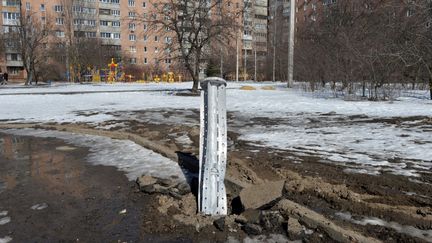 Une fusée de 300mm, qui semble contenir des sous-munitions, enfoncée dans le sol après un bombardement dans la banlieue nord de Kharkiv, le 21 mars 2022. (SERGEY BOBOK / AFP)