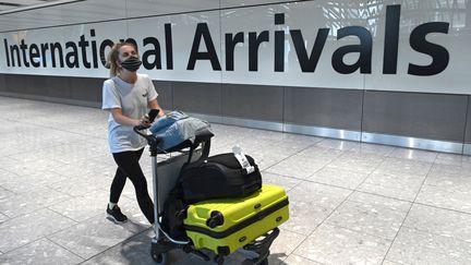 Une passagère arrive masquée à l'aéroport de Heathrow, à Londres (Grande-Bretagne) le 10 juillet 2020 (DANIEL LEAL-OLIVAS / AFP)