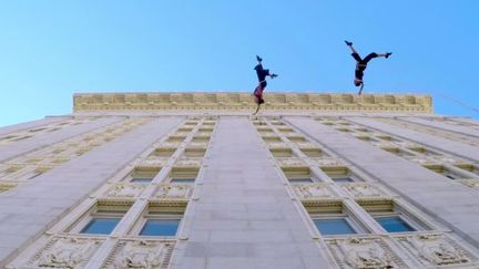 Capture d'&eacute;cran - Amelia Rudolph et Roel Seeber du groupe Bandaloop dansent accroch&eacute;s &agrave; des fils, &agrave; la verticale de l'hotel de ville d'Oakland en CCalifornie (GOPRO / BANDALOOP / YOUTUBE)