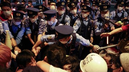 À l'extérieur du stade, plusieurs manifestants se sont réunis dans les rues de Tokyo pour s'opposer à la tenue de ces Jeux. La pandémie de coronavirus continue de s'étendre dans le pays, qui a déclaré l'état d'urgence sanitaire le 8 juillet, avec plus de 5 000 cas quotidiens&nbsp;reconnus.&nbsp;Plusieurs cas de Covid-19 ont déjà été détectés&nbsp;au sein même du village olympique. (YUKI IWAMURA / AFP)