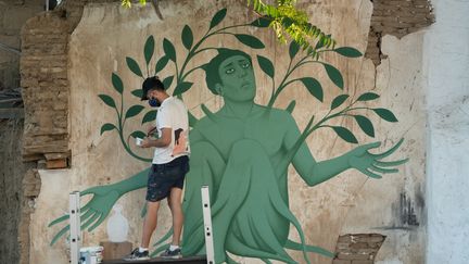 L'artiste grec Fikos, qui se décrit comme un "néo-muraliste", travaille sur l'une de ses peintures murales dans la capitale chypriote Nicosie le 4 juin 2021. (DAVID VUJANOVIC / AFP)