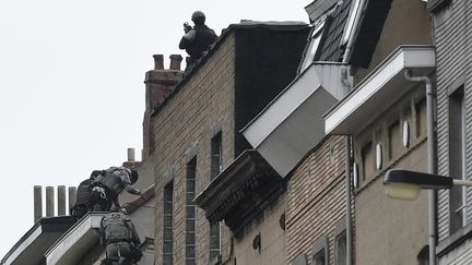 Des forces de sécurité grimpent sur des immeubles à Molenbeek dans la banlieue de Bruxelles, le 16 novembre 2015. (JOHN THYS / AFP)