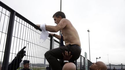 Le DRH d'Air France, Xavier Broseta, escalade le grillage, torse nu et chemise en lambeaux, le 5 octobre 2015 à Roissy (Val-d'Oise). (KENZO TRIBOUILLARD / AFP)