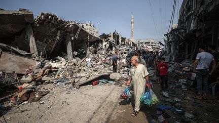 Des habitants de Gaza regardent les bâtiments complètement détruits après des frappes israéliennes, le 28 octobre 2023. (MUSTAFA HASSONA / ANADOLU / AFP)