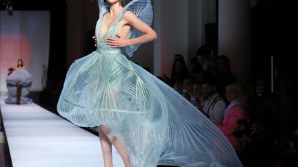 Jean Paul Gaultier s'est inspiré de la mer et du Japon pour une collection graphique toute en "légèreté et transparence". Sur le podium, la pin-up et effeuilleuse américaine Dita Von Teese et Anna - la fille de Pat Cleveland top-model star des seventies - qui présente la robe de mariée longue blanche et transparente d'inspiration japonaise. Cette mariée "est une tornade, un ouragan et en même temps elle est en elle seule un poème", s'émerveille le couturier. Sans oublier Coco Rocha, professionnelle de la danse irlandaise, en robe cage d'organza turquoise. Bleu, vert, corail - les couleurs et les motifs sont inspirés de la vie aquatique pour cette collection qui porte aussi un message écologique : "les choses sont belles et on ne tue pas les animaux pour autant", souligne le couturier qui s'est engagé à renoncer à la fourrure. Les motifs japonais apparaissent dans des Obi, ceintures de kimono revisitées, et des ceintures "îlots" plissées. "Je voulais que tout soit plissé, même les cheveux", dit le couturier qui a envoyé une invitation plissée pour son défilé. "Je les voulais comme ceux de geisha, avec un effet après amour qui est très beau", souligne-t-il encore. 
 (Francois Mori/AP/SIPA)