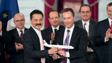 François Hollande entouré de Rusdi Kirana (avec la moustache) et de Fabrice Bregier, PDG d'Airbus, lors de la signature de la vente record d'Airbus à la compagnie indonésienne Lion Air à l'Elysée, le 18 mars 2013 (BERTRAND LANGLOIS / AFP)