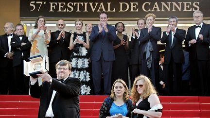 Dix ans après Pulp Fiction, Quentin Tarantino revient à Cannes comme Président du Jury. Cette année-là, c'est&nbsp;Fahrenheit 9/11&nbsp;de Michael Moore qui sera récompensé par la Palme d'or. Le documentariste l'exhibe sur les marches du palais des festivals et sous les applaudissements du jury (FRANCOIS GUILLOT / AFP)