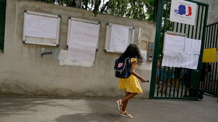 Une élève devant les panneaux "école abandonnée, on en a marre, nous ne voulons plus être sacrifiés" accrochés sur les murs d'une école à Marseille. Image d'illustration. (NICOLAS TUCAT / AFP)