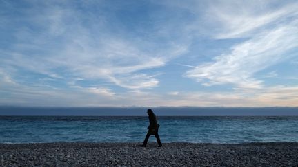 Un homme marche sur la plage déserte, à Nice, le 16 février 2021. (VALERY HACHE / AFP)