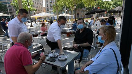 Des clients masqués à la terrasse d'un bar sur les Ramblas de Barcelone (Espagne), le 25 mai 2020 (LLUIS GENE / AFP)