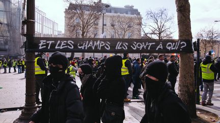 Des manifestants cagoulés et des "gilets jaunes" sur les Champs-Elysées, le 16 mars 2019.&nbsp; (MARIE MAGNIN / HANS LUCAS / AFP)