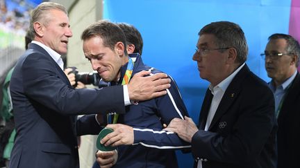 Renaud Lavillenie, en pleurs, est réconforté par Sergueï Bubka et le président du CIO, Thomas Bach. (JULIEN CROSNIER / DPPI MEDIA / AFP)