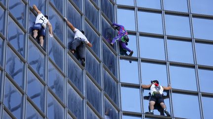 Le Français Alain Robert escalade une tour de La Défense, près de Paris, pour protester contre le pass sanitaire, le 7 septembre 2021. (THOMAS SAMSON / AFP)